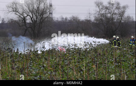 Oberhausen-Rheinhausen, Deutschland. 23 Jan, 2018. Feuerwehrmänner löschen des Feuers von den Trümmern an der Unfallstelle, wo ein kleines Flugzeug und ein Hubschrauber in der Luft in Oberhausen-Rheinhausen, Deutschland, 23. Januar 2018 Credit abgestürzt: dpa Picture alliance/Alamy leben Nachrichten Stockfoto