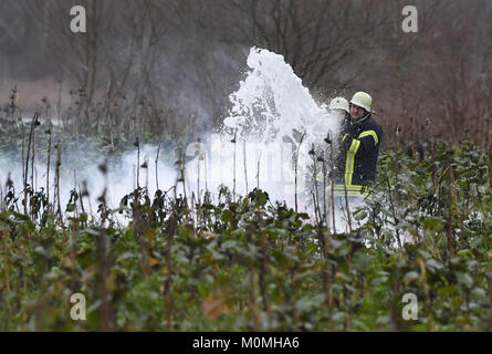 Oberhausen-Rheinhausen, Deutschland. 23 Jan, 2018. Feuerwehrmänner löschen des Feuers von den Trümmern an der Unfallstelle, wo ein kleines Flugzeug und ein Hubschrauber in der Luft in Oberhausen-Rheinhausen, Deutschland, 23. Januar 2018 Credit abgestürzt: dpa Picture alliance/Alamy leben Nachrichten Stockfoto