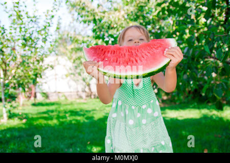 Kleines Mädchen ihr Gesicht verstecken durch grosse Scheibe Wassermelone. Sommer. Outdoor. Nicht erkennbare Kind. Das Geben, Aktien Stockfoto