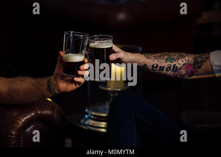 Nahaufnahme von zwei Männern toasten ihre Pints. Stockfoto