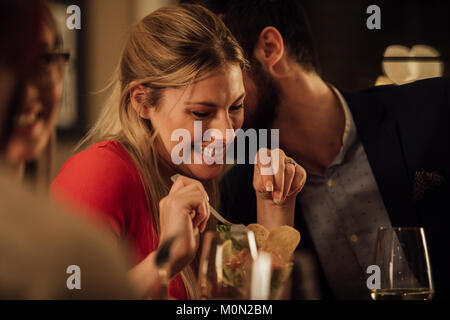 Paar sind romantisch, während Sie eine Mahlzeit in einem Restaurant. Der Mann ist die Frau Küssen auf die Wange und sie ist zu kichern. Stockfoto