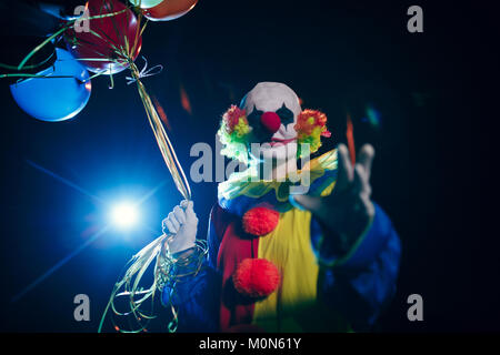 Bild der lächelnde Clown mit Luftballons gegen den Hintergrund von brennenden Laterne Stockfoto