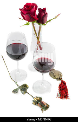 Zwei Rosen Rotwein Gläser und Metallische Rose und Granatapfel auf weißem Hintergrund Valentines Tag Zusammensetzung Stockfoto