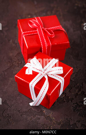 Red Geschenkboxen mit Bändern mit Bögen und dekorative Seide Herzen auf braunem Hintergrund gebunden. Hintergrund für den Valentinstag. Flach. Stockfoto