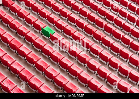 Eine grüne Sitz unter den roten Sitze in einem Stadion, stehend aus der Menge Konzept Stockfoto