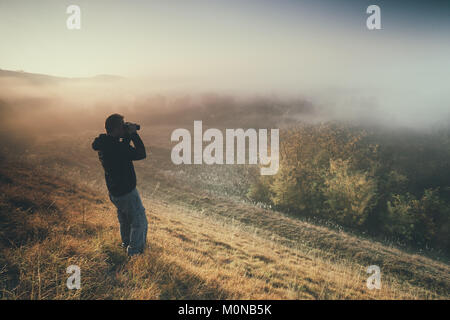 Der Mensch ist Wandern und Beobachten der Natur mit dem Fernglas in den Morgen. Stockfoto