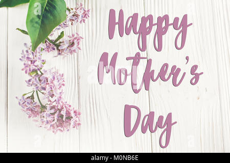 Happy Mother's Day text Zeichen, Grußkarte. Glückliche Mütter Tag. schönen lila Blumen auf rustikalen weiß Holz- Hintergrund der Ansicht von oben. happy Tag der Frauen. Stockfoto