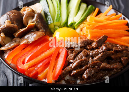 Köstlichen Bibimbap mit Rindfleisch, Eier, Gemüse, Shiitake und Reis close-up in einer Schüssel auf dem Tisch. Horizontale Stockfoto