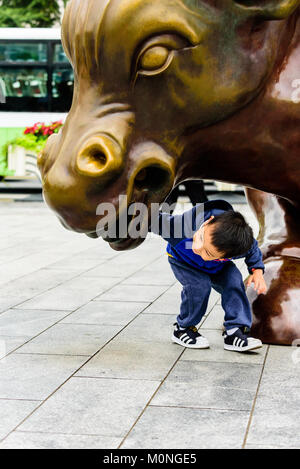 Shanghai, China. Ein junges Kind untersucht den Stier Statue im Finanzdistrikt am Bund in Shanghai, China. Credit: Benjamin Ginsberg Stockfoto