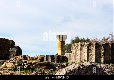 Gefallenen Spalten mit Unkraut und Wildblumen im antiken Korinth in Griechenland mit einem verbleibenden Spalte der Tempel des Zeus im Hintergrund Stockfoto