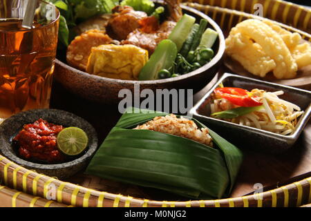 Nasi Tutug Oncom, der Sundanesischen Teller Reis mit fermentierten Sojabohnen; mit verschiedenen Beilagen serviert. Stockfoto