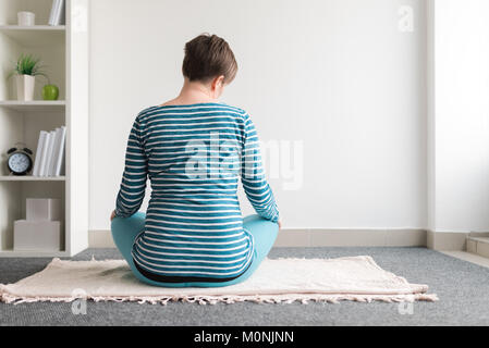 Schwangeren Yoga Übung zu Hause. Schwangerschaft Yoga und drinnen Fitness Concept. Unbenotete kontrastarmen Aufnahmen mit natürlichen Fenster Licht. Stockfoto