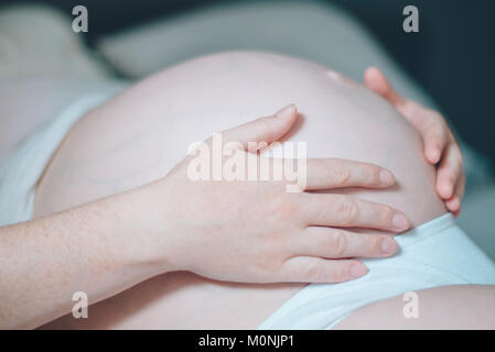 Schwangere Frau Bauch streicheln im Schlafzimmer zu Hause, kurz bevor die Wehen und Geburt, selektiven Fokus Stockfoto