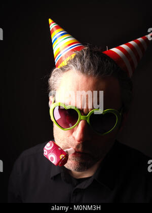 Karneval oder Geburtstag konzeptionelle Porträt eines Mannes auf einem dunklen Hintergrund Stockfoto