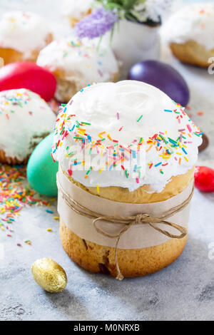Ostern Komposition. Ostern Kuchen dekoriert weiße Glasur und bunten Zucker Streusel auf einen konkreten Hintergrund. Stockfoto