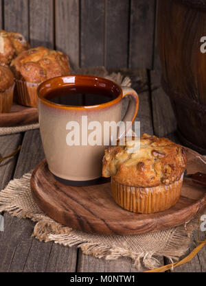 Banane Mutter Muffin und Tasse Kaffee auf einer Holzplatte in einem rustikalen Ambiente Stockfoto