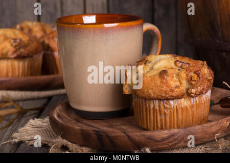 Nahaufnahme einer Banane nuss Muffins und Kaffee Tasse auf einer Holzplatte in einem rustikalen Ambiente Stockfoto