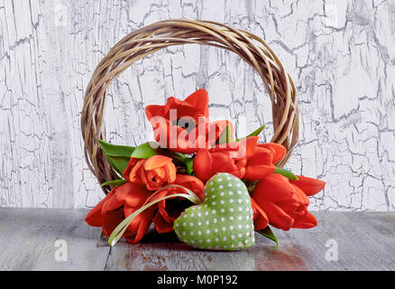 Feder Dekoration mit hölzernen Kranz, rote Tulpen und knackte stugged Herz auf weißem Hintergrund. Stockfoto