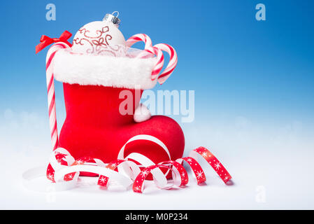 Santa's Boot mit Zuckerstangen und Weihnachten Dekorationen auf blauen Gradienten Hintergrund, Text Raum Stockfoto