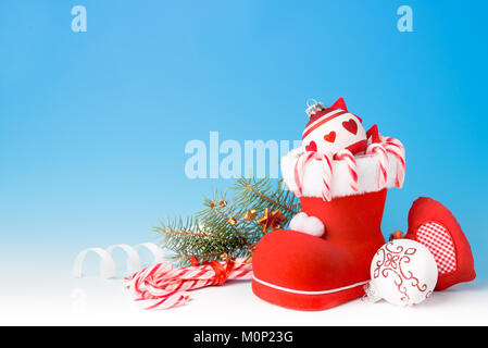 Santa's Boot mit Zuckerstangen und Weihnachten Dekorationen auf blauen Gradienten Hintergrund, Raum Stockfoto