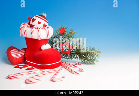 Santa's Boot mit Zuckerstangen und Weihnachten Dekorationen auf blauen Gradienten Hintergrund, Raum Stockfoto