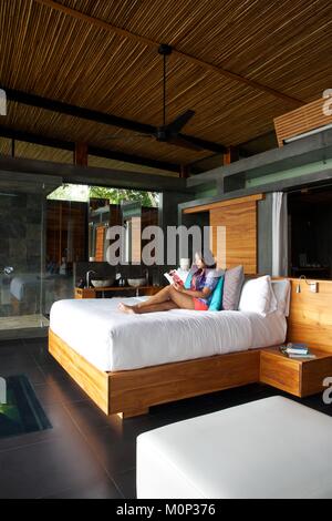 Costa Rica, Halbinsel Osa, Frau im Bett ihrer zeitgenössischen Design Suite der Ecolodge Kura Design Villas Stockfoto