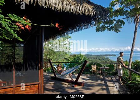 Costa Rica, Halbinsel Osa, Paar auf der Terrasse fo der Ecolodge Lapa Rios mit Blick auf den Wald und den Pazifischen Ozean Stockfoto