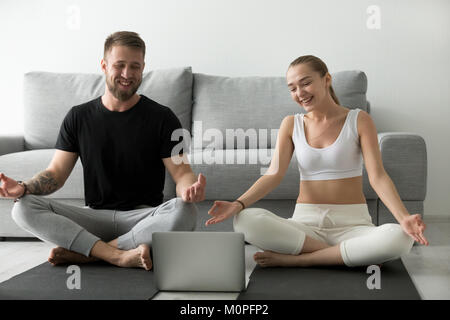 Lächelndes Paar lernen Yoga Übungen Video auf Laptop Stockfoto