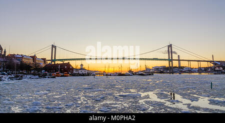 Göteborg - schönen Sonnenuntergang bei Frozen Gota Fluss mit Hisingsleden Brücke im Hafenviertel im Winter Stockfoto