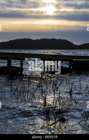 Dramatischer dark Sonnenuntergang über hölzerne Seebrücke auf See in Ingared in der Nähe von Göteborg, Schweden Stockfoto