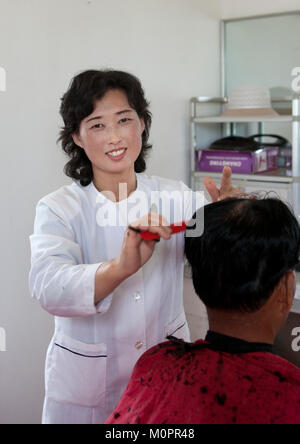 Lächelnd Nordkoreanischen friseur Haare schneiden, Süd-pyongan Provinz, Chongsan-ri Kooperative Farm, Nordkorea Stockfoto