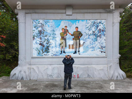 Ausländische Tourist, der ein Bild von einem Propaganda Fresko Kim Il-Song als Kind mit seinen Eltern, Ryanggang Provinz, Samjiyon, Nordkorea Stockfoto