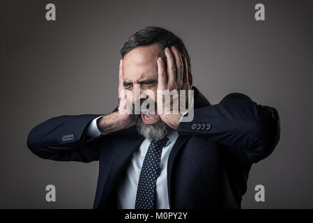 Wütend Geschäftsmann mit einer schrecklichen Kopfschmerzen Stockfoto