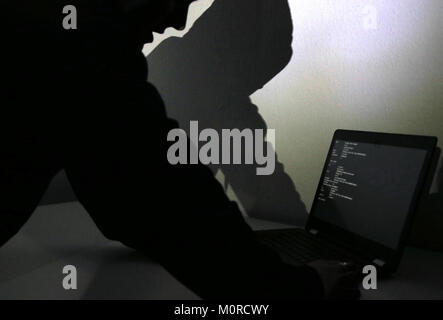 München, Deutschland. 17 Jan, 2018. ILLUSTRATION - Illustration - Der Schatten der ein Mann mit einem Hoodie erscheint auf der Wand hinter einem Laptop in München, Deutschland, 17. Januar 2018. Credit: Lisa Forster/dpa/Alamy leben Nachrichten Stockfoto