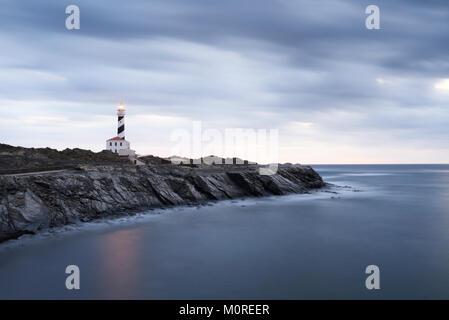 Lange Belichtung geschossen von favaritx Leuchtturm in einem bewölkten am frühen Morgen in der Dämmerung. Menorca, Balearen, Spanien. Stockfoto