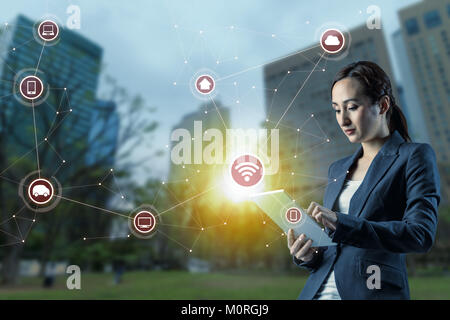 Junge Frau mit Tablet PC und Internet der Dinge Konzept. smart City. Drahtlose Kommunikation Netzwerk. abstract mixed Media. Stockfoto