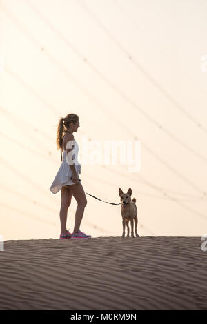 Dubai, VAE - 27.Oktober 2017: Hund und eine Person für einen Spaziergang in der Wüste bei Sonnenuntergang. Stockfoto