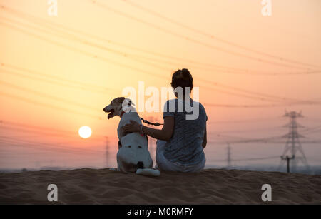 Dubai, VAE - 27.Oktober 2017: Hund und eine Person für einen Spaziergang in der Wüste bei Sonnenuntergang. Stockfoto