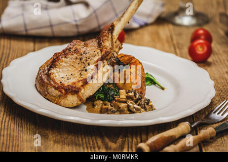 Gebackene Schnitzel oder Kotelett mit Pilzsauce und Kartoffeln mit Spinat Stockfoto