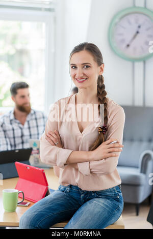 Porträt eines erfolgreichen Unternehmer sitzen auf einem Schreibtisch in der s Stockfoto