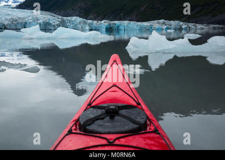 Eisberge schwimmen um ein rotes Kajak vor der Spencer Gletscher in Alaska. Die See ist ruhig und glatt, kaum von der Kajak gestört. Stockfoto