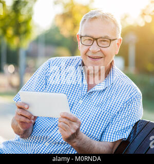 Outdoor Portrait von Happy älterer Mann, der sich mit digitalen Tablet. Stockfoto