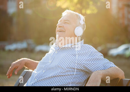 Outdoor Portrait von älteren Mann, der Zuhören ist Musik über Kopfhörer. Stockfoto