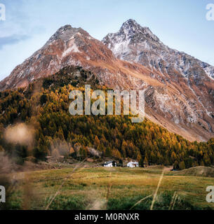 Kleine Häuser in Maloja Dorf gegen die Berge bei Sonnenuntergang im Herbst, Malojapass, Schweiz. Stockfoto