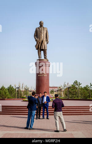 Usbekische Menschen posieren für ein Foto unter der Statue von Islam Karimow, Samarkand, Usbekistan Stockfoto