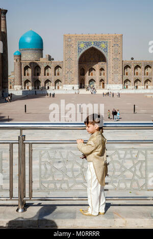 Eine junge USBEKISCHE Hochzeit Gast (Seite Junge) wartet zu haben sein Foto an der Registan Komplexes, Samarkand, Usbekistan teilgenommen Stockfoto