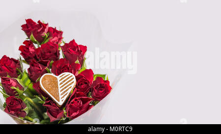 Strauß roter Rosen und dekorative Herzen für gutes Glück. Blumen zum Valentinstag Hintergrund mit Lebkuchen. Muttertag, Tag der Frauen, Geburtstag, Hochzeit. Stockfoto