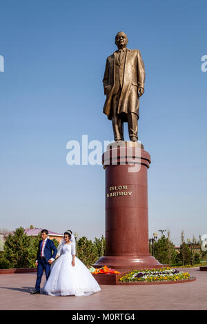 Eine 'Just Married' Paar posieren für ein Hochzeit Foto Neben der Statue des verehrten ehemaligen Präsidenten Islam Karimow, Samarkand, Usbekistan Stockfoto
