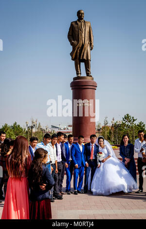 Eine Hochzeitsfeier posiert für ein Foto Neben der Statue des verehrten ehemaligen Präsidenten Islam Karimow, Samarkand, Usbekistan Stockfoto