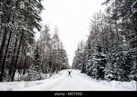 Eine Frau tun Winter star springt auf Frost und Schnee Straße in Labanoro Regional Park, Litauen abgedeckt. Stockfoto